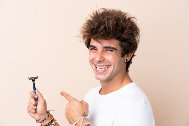 Uomo che rade la sua barba sopra la parete isolata