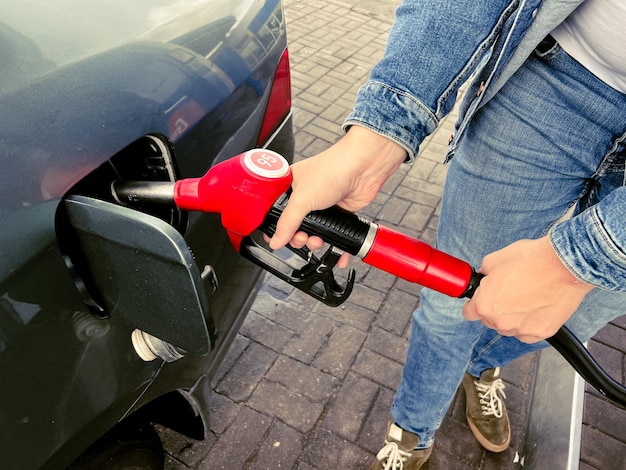 Uomo che rifornisce l'auto dalla stazione di servizio Uomo barbuto caucasico che riempie l'auto di benzina