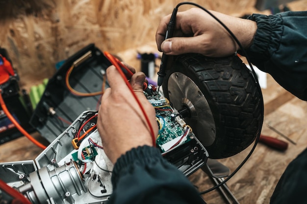 Uomo che ripara scooter elettrico in officina speciale. Officina specializzata per la riparazione di scooter elettrici e biciclette.