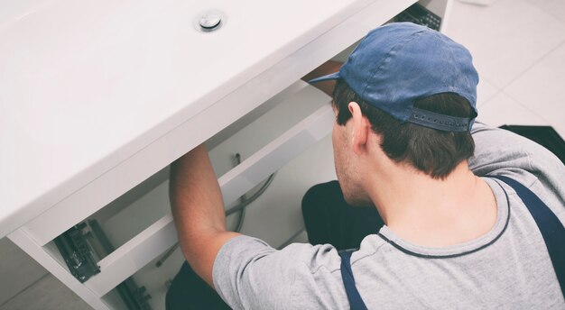 Uomo che ripara un lavandino in bagno