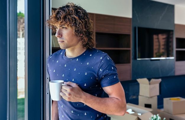 Uomo che riposa dal disimballaggio di scatole in movimento che beve caffè