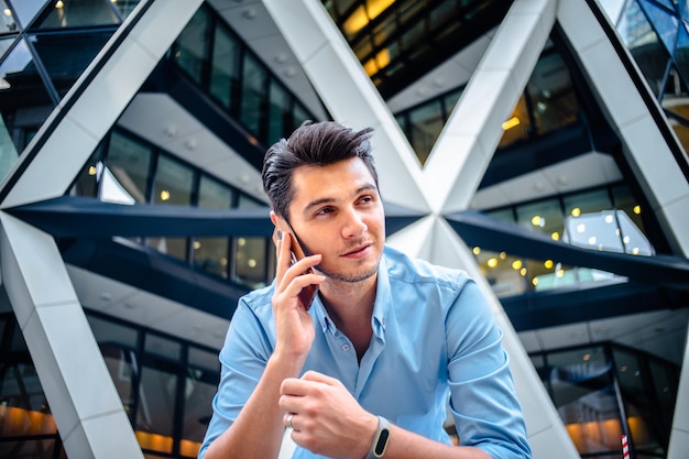 Uomo che risponde allo smartphone mentre è in piedi in città