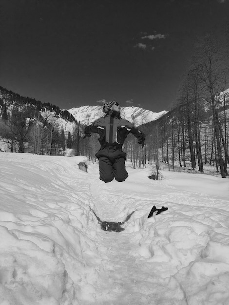 Uomo che salta su una terra innevata contro il cielo.