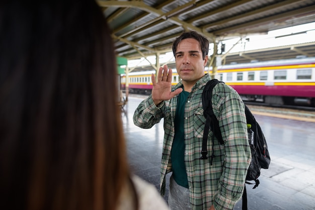 Uomo che saluta alla giovane donna turistica asiatica nella stazione ferroviaria