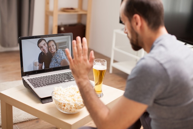 Uomo che saluta i suoi amici in una videochiamata durante la quarantena.