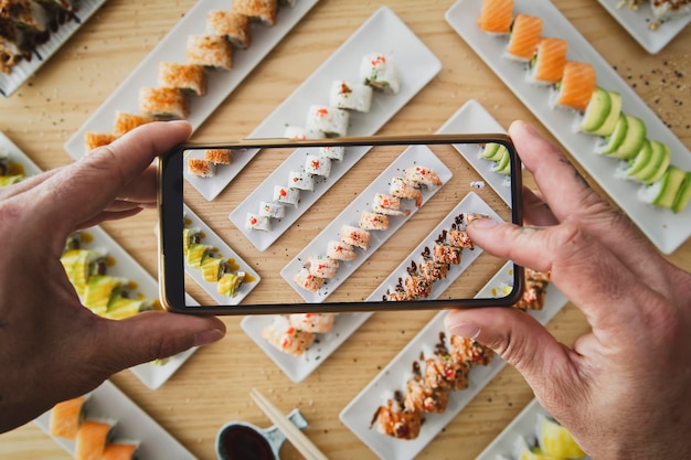 Uomo che scatta foto di cibo giapponese sushi california roll