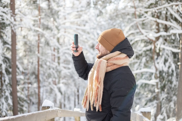 Uomo che scatta foto di una foresta innevata