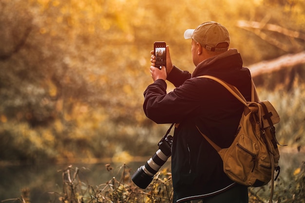 Uomo che scatta una foto con il suo telefono mentre ha la sua macchina fotografica