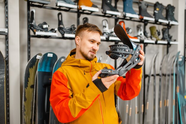 Uomo che sceglie il fissaggio dello scarpone da sci, shopping nel negozio di articoli sportivi.