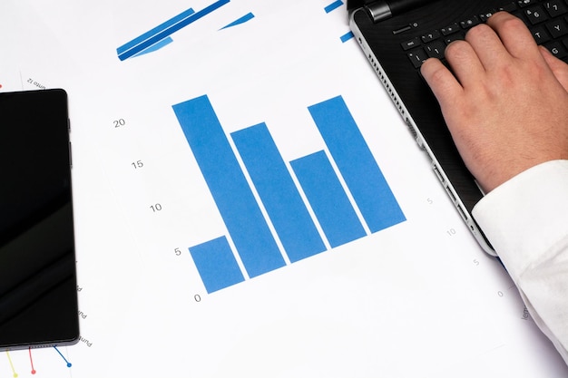 uomo che scrive nel taccuino sopra i grafici con i dati