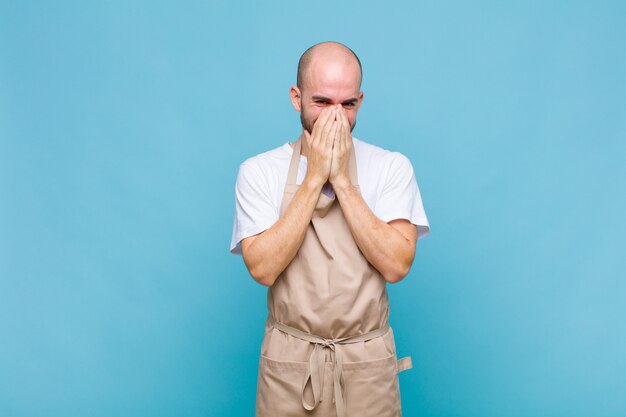 Uomo che sembra felice, allegro, fortunato e sorpreso che copre la bocca con entrambe le mani