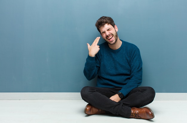 uomo che sembra infelice e stressato, gesto suicida facendo segno di pistola con la mano, indicando la testa