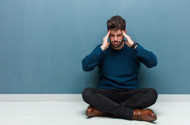 Uomo che sembra stressato e frustrato, che lavora sotto pressione con un mal di testa e turbato da problemi