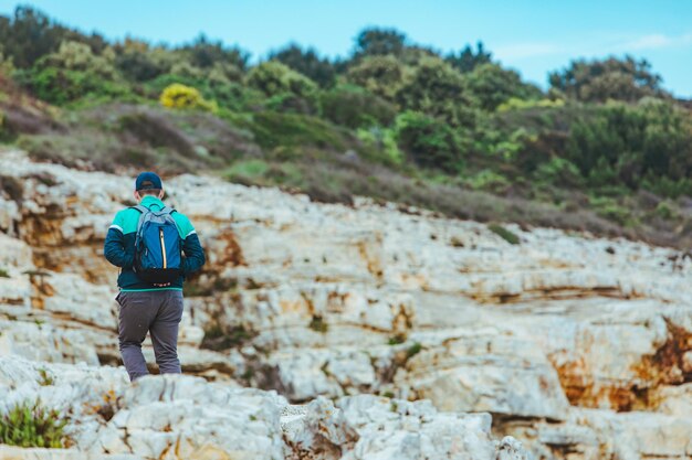 Uomo che si arrampica dal concetto di viaggio di collina rocciosa