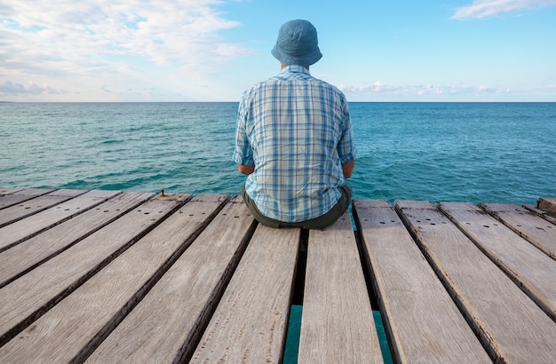 Uomo che si distende sul molo sul mare