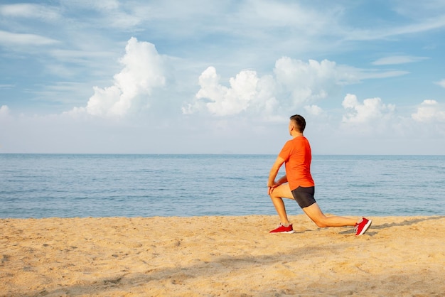 Uomo che si esercita sull'allenamento in spiaggia all'alba del sole all'alba sullo stile di vita sano all'aperto della spiaggia del mare