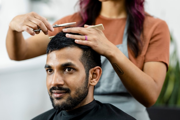 Uomo che si fa tagliare i capelli da un parrucchiere in un barbiere