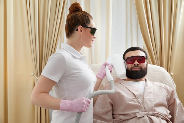 Uomo che si faceva rimuovere i capelli con il laser in faccia da un cosmetologo.