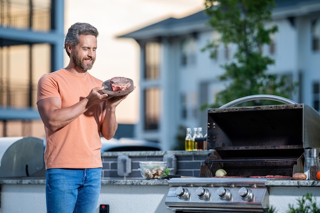 Uomo che si gode il barbecue uomo che griglia la sua carne preferita cuoco che mostra le sue tecniche di barbecue durante l'evento di cottura spazio copia Grill aficionado paradise