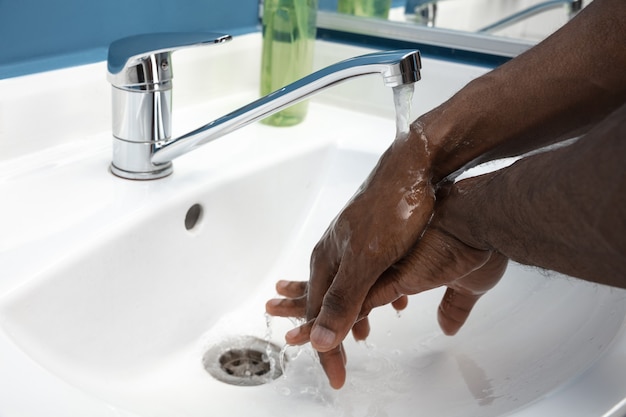 Uomo che si lava accuratamente le mani con sapone e disinfettante, primo piano.