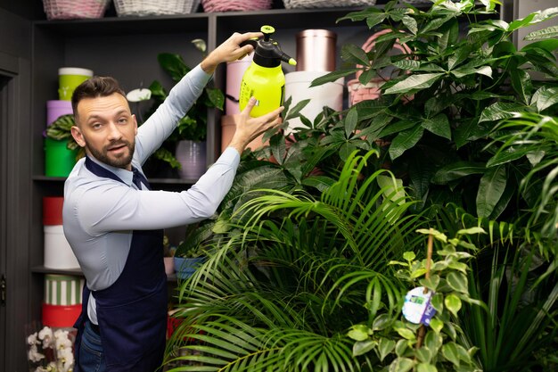 uomo che si prende cura delle piante in vaso spruzzandole con uno spruzzatore da giardino.