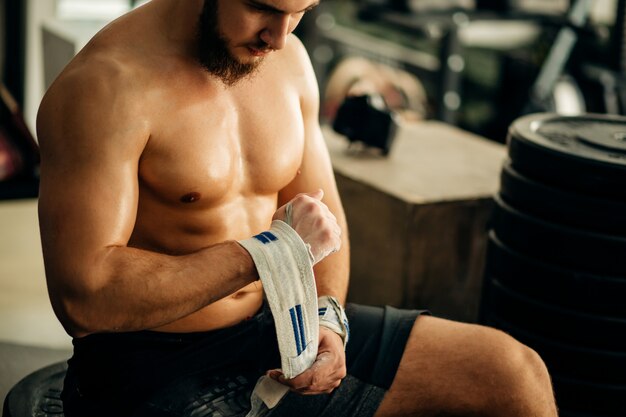 Uomo che si prepara per l'allenamento, avvolgendo le mani con nastro adesivo