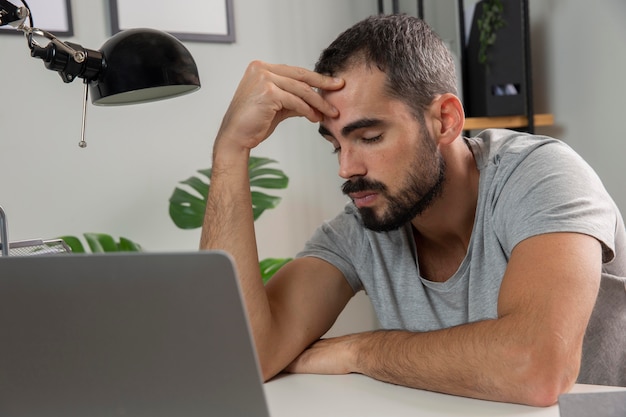 Uomo che si sente stanco mentre lavora da casa