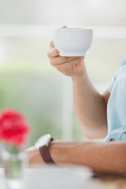 Uomo che si siede nel caffè con caffè