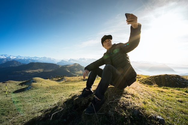 Uomo che si siede su roccia e selfie in trevel