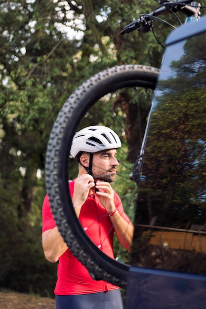 Uomo che si veste accanto al suo furgone per andare in bicicletta