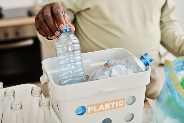 Uomo che smista le bottiglie di plastica nei contenitori