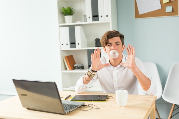 Uomo che soffia bolla di gomma da masticare in ufficio