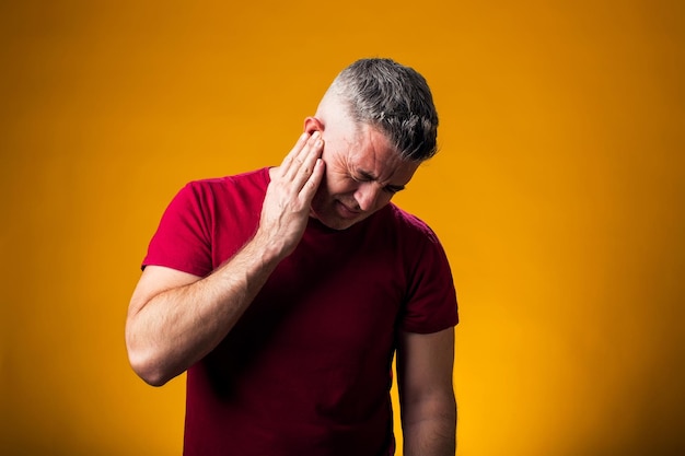 Uomo che soffre di dolori all'orecchio Mano sull'orecchino Concepto di assistenza sanitaria e medicina