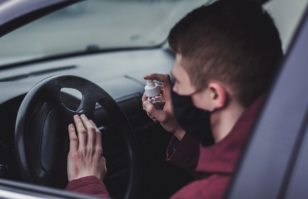 Uomo che spruzza spray disinfettante antibatterico sul volante