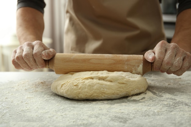 Uomo che stende la pasta sul tavolo da cucina da vicino