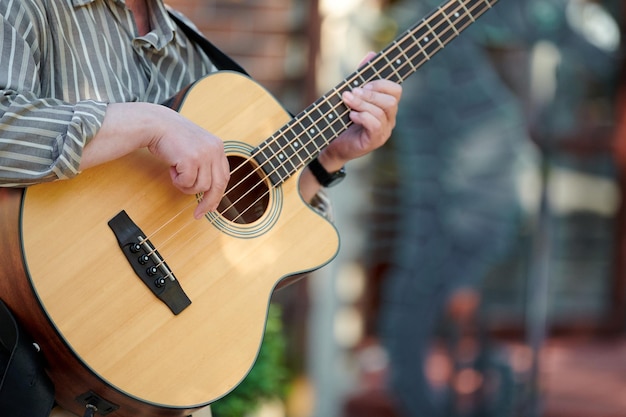 Uomo che suona il basso acustico all'evento all'aperto vista ravvicinata al collo della chitarra