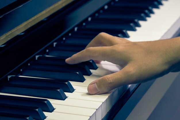 Uomo che suona il pianoforte in studio con la mano offuscata