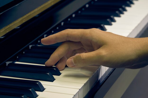 Uomo che suona il pianoforte in studio con la mano offuscata