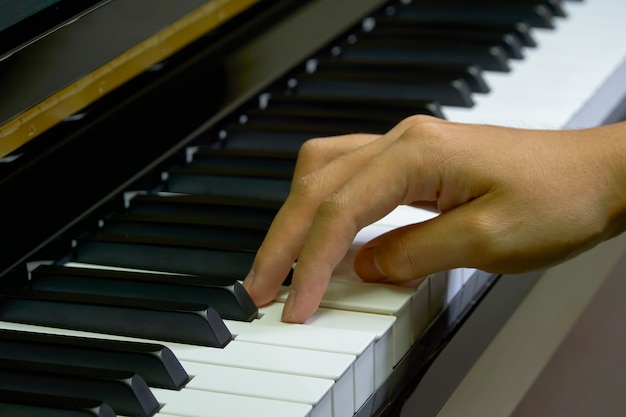 Uomo che suona il pianoforte in studio con la mano offuscata