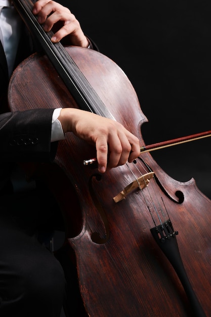 Uomo che suona il violoncello su sfondo scuro