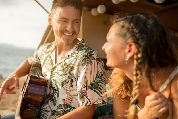 Uomo che suona la chitarra accanto a una donna in un furgone