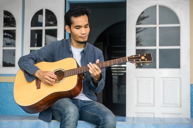 Uomo che suona la chitarra felice tempo libero a casa