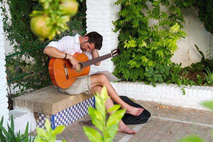 Foto uomo che suona la chitarra mentre è seduto su una panchina nel cortile