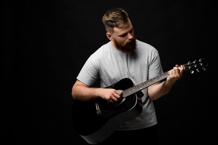 Foto uomo che suona la chitarra su uno sfondo nero