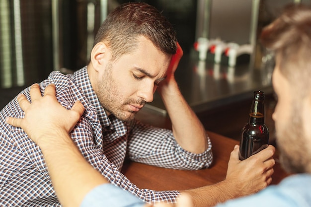 Uomo che sveglia il suo amico ubriaco al bancone del bar