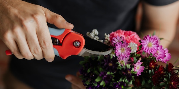 Uomo che taglia fiori nelle sue mani mentre fa un bouquet