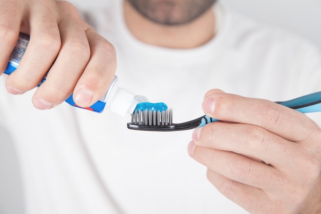 Uomo che tiene dentifricio e spazzolino da denti blu