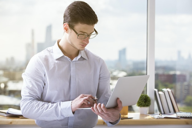 Uomo che tiene e utilizza il computer portatile