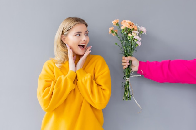 uomo che tiene fiori per una donna in abiti gialli su sfondo grigio Happy day