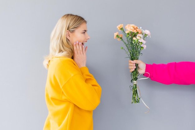 uomo che tiene fiori per una donna in abiti gialli su sfondo grigio Happy day